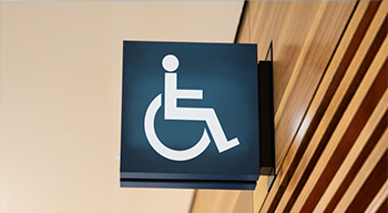 Znak wiszący na ścianie przedstawiający osobę na wózku