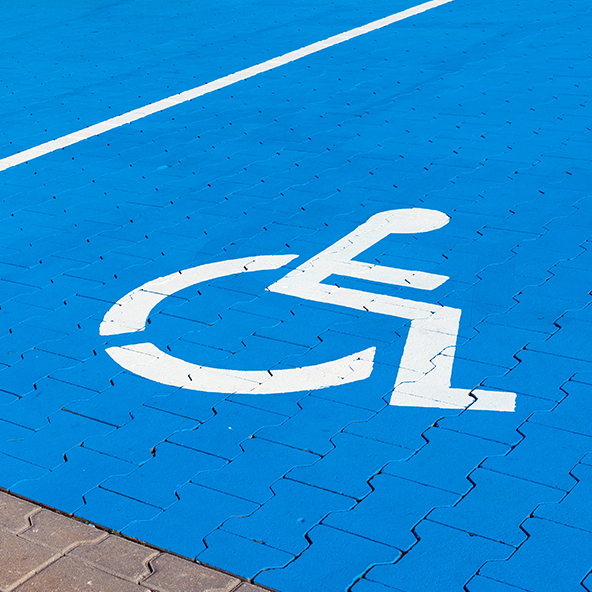 Biały symbol osoby na wózku na niebieskim tle.