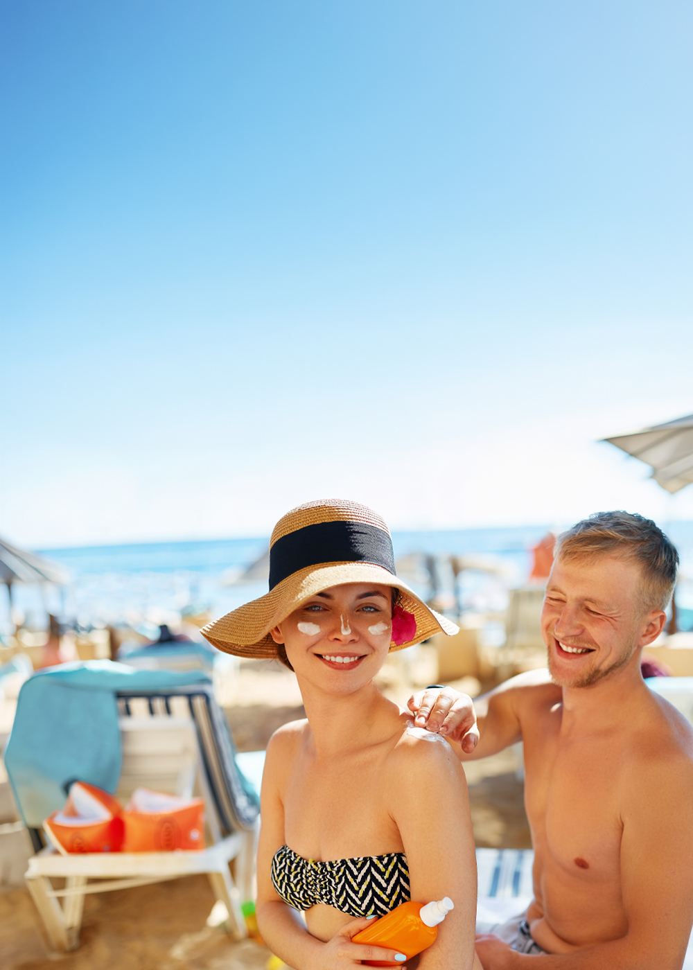 Event lato pod lupą w M1 Zabrze. Para odpoczywająca na plaży. Mężczyzna smarujący swoją uśmiechniętą kobietę kremem.